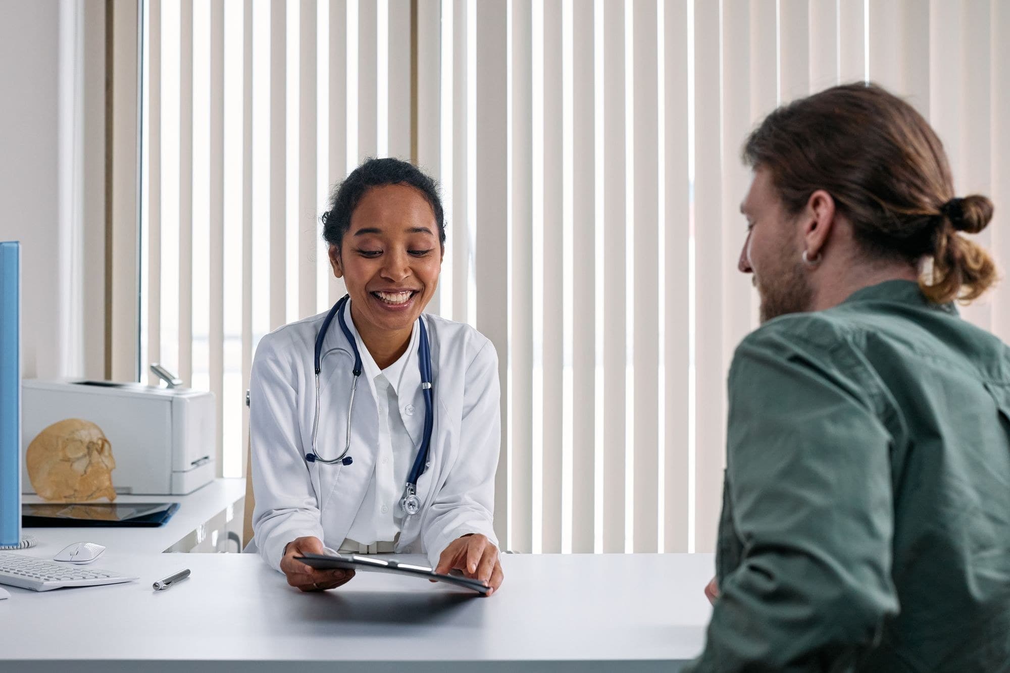 A clinician speaking with an adult patient during a consultation. Demonstration imagery — not Peak Mark staff.