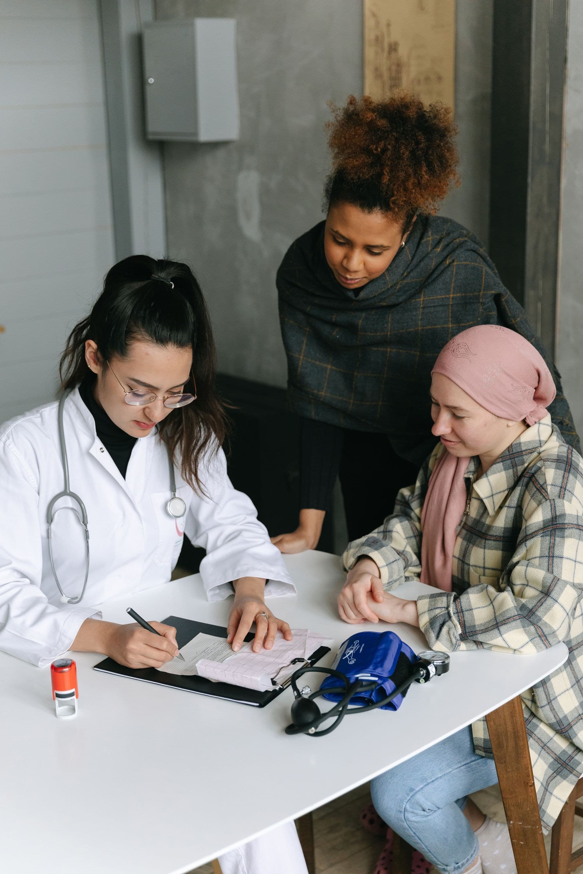 A patient and companion speaking with a clinician during a visit. Demonstration imagery — not Peak Mark patients or staff.